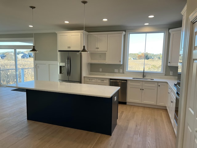 kitchen with white cabinets, stainless steel appliances, hanging light fixtures, and sink