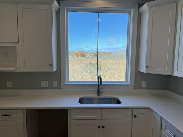 kitchen featuring sink, white cabinets, and light stone counters