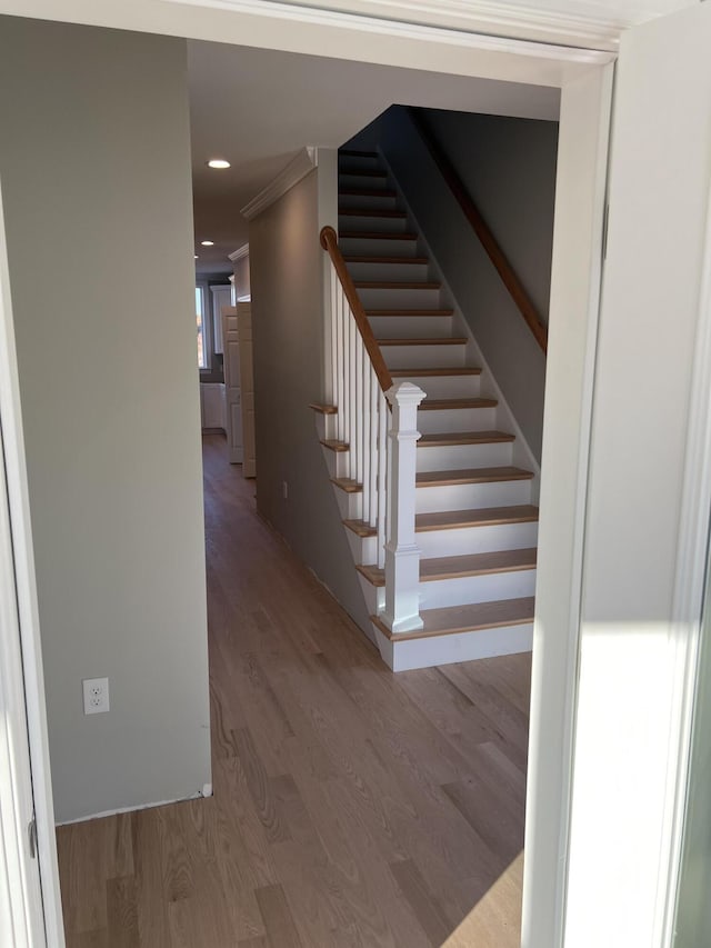 stairs with crown molding and hardwood / wood-style floors