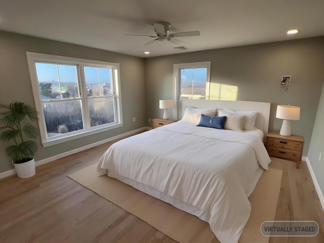 bedroom featuring ceiling fan, multiple windows, and light hardwood / wood-style flooring