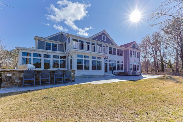 back of house with a patio, a balcony, an outdoor kitchen, a yard, and a sunroom