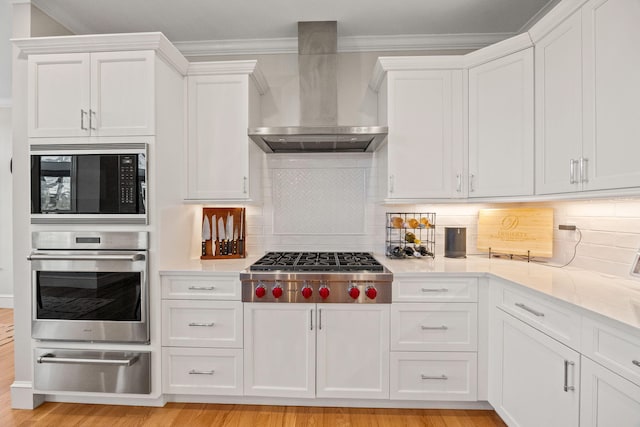 20 Chase St, West Harwich, MA 02671 - kitchen with stainless steel appliances, wall chimney range hood, a warming drawer, white cabinets, and crown molding