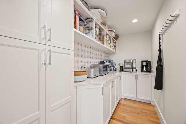 bar with light hardwood / wood-style flooring and white cabinets