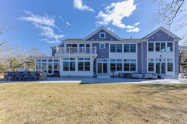 rear view of house with a yard, a sunroom, a patio, and a balcony