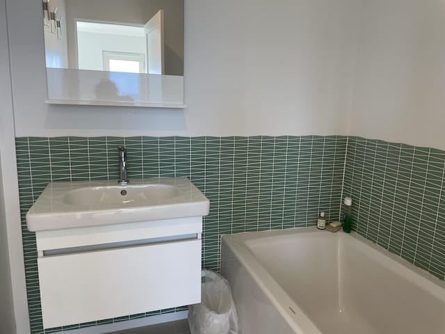 535 Commercial St Unit U1, Provincetown, MA 02657 - bathroom with tile walls, a tub, and vanity