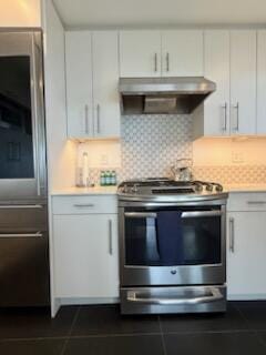kitchen with decorative backsplash, light countertops, under cabinet range hood, dark tile patterned flooring, and stainless steel electric range oven