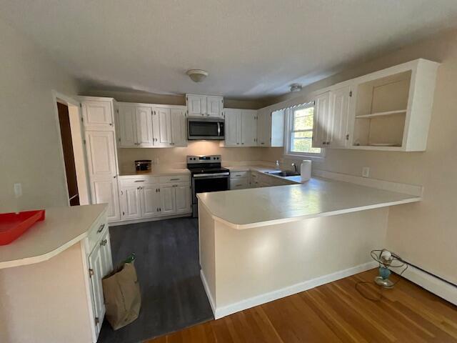 103 Braeside Rd, West Falmouth, MA 02540 - kitchen with dark wood finished floors, appliances with stainless steel finishes, a peninsula, and light countertops