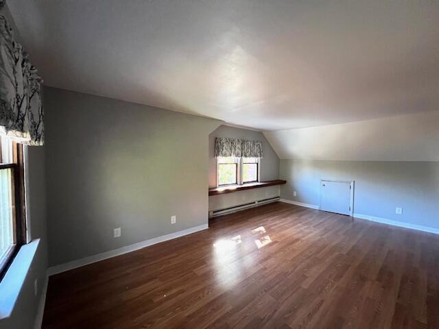 additional living space featuring a baseboard radiator, lofted ceiling, and dark hardwood / wood-style flooring