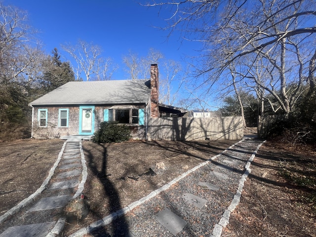 view of front of property featuring roof with shingles, a chimney, and fence