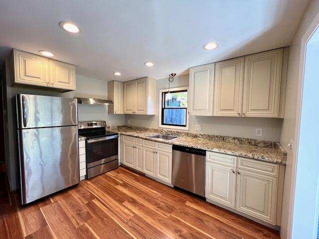 kitchen with stainless steel appliances, white cabinetry, sink, and light hardwood / wood-style flooring