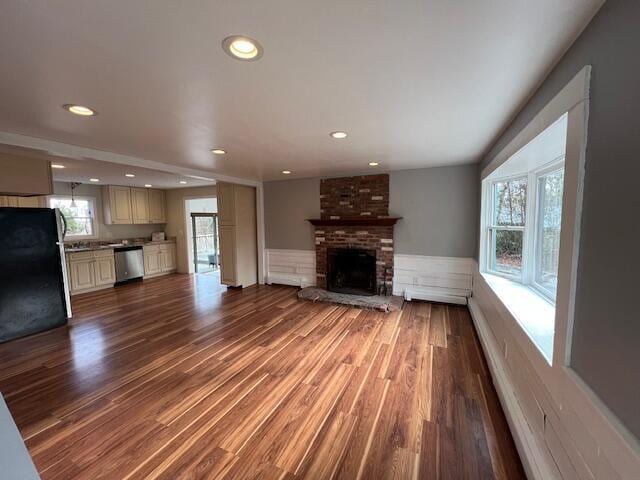 unfurnished living room featuring a wainscoted wall, a fireplace, wood finished floors, and recessed lighting