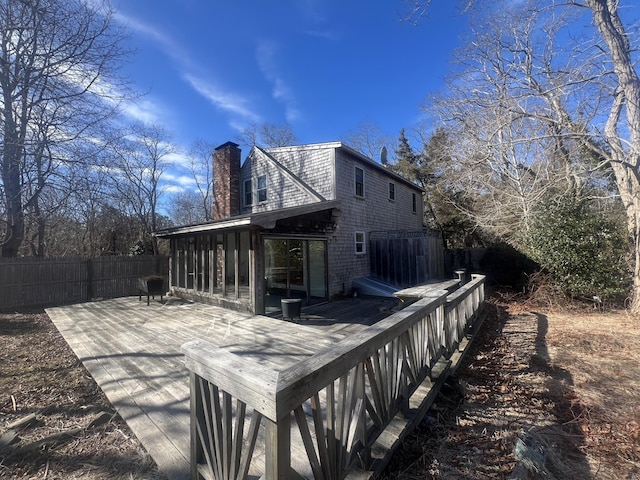 view of home's exterior with a chimney, fence, and a sunroom