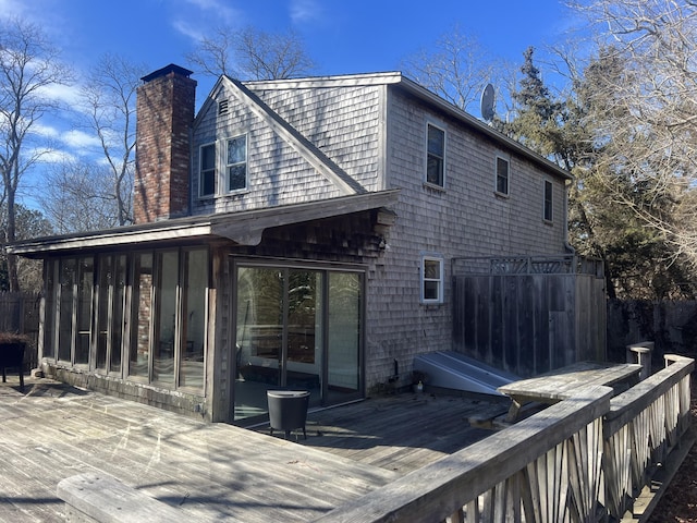 rear view of house with a sunroom, a chimney, and a wooden deck