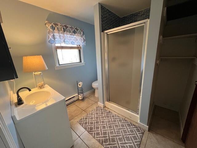 bathroom with a shower with door, baseboard heating, tile patterned flooring, vanity, and toilet