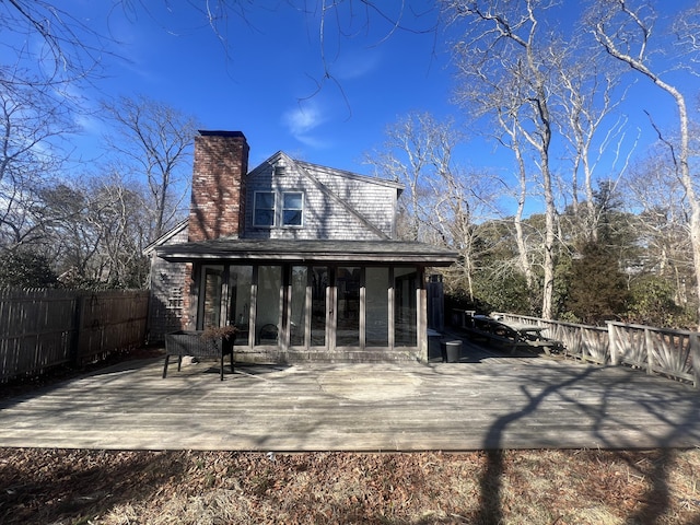 rear view of property featuring a sunroom, fence, and a deck