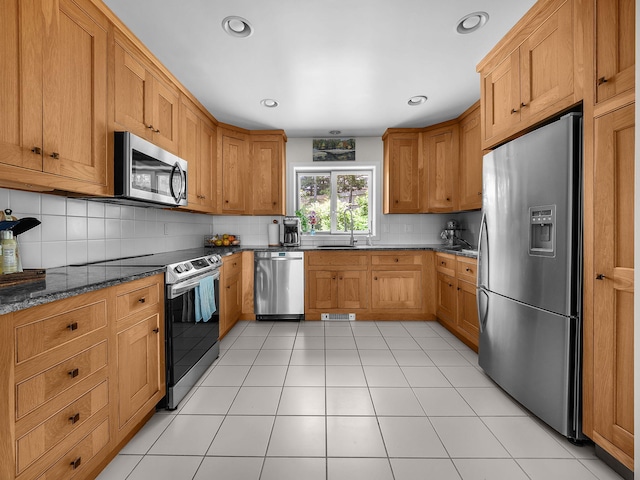 50 View Crest Dr, Falmouth, MA 02540 - kitchen with stainless steel appliances, decorative backsplash, dark stone counters, and brown cabinetry