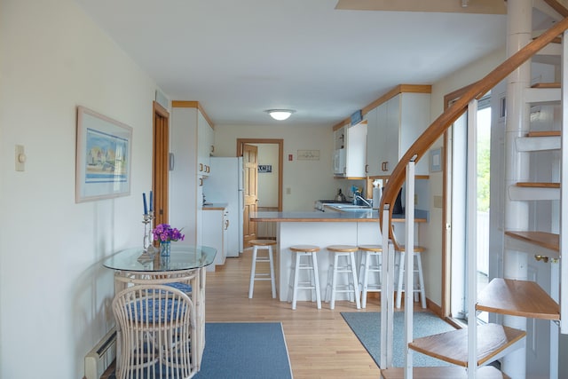 99 Shore Blvd Unit A, East Sandwich, MA 02537 - kitchen featuring light wood finished floors, a breakfast bar, a peninsula, white cabinets, and white appliances