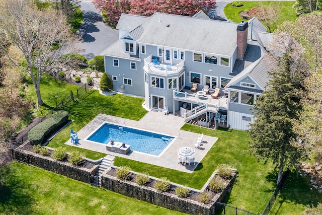 back of property with a balcony, a chimney, a patio area, and stairs