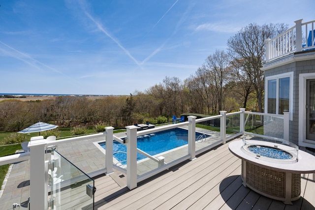 outdoor pool with an outdoor fire pit, a wooden deck, and a jacuzzi