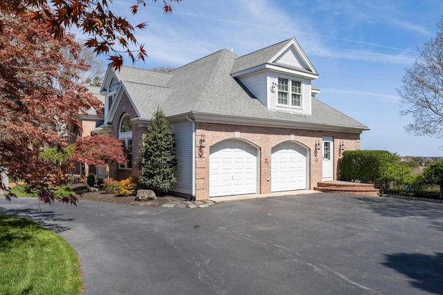 view of side of home featuring brick siding, asphalt driveway, and roof with shingles