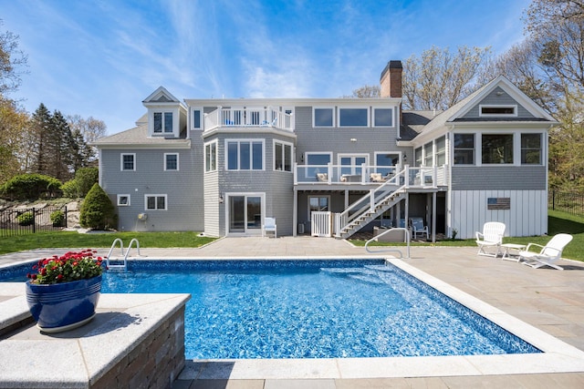 rear view of house featuring stairs, a balcony, a patio area, and a chimney