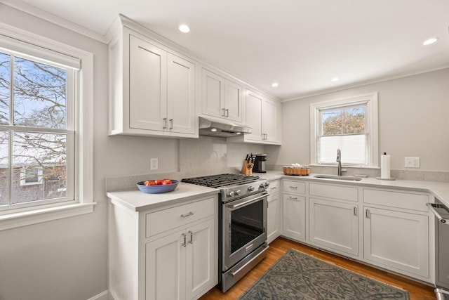 kitchen with sink, stainless steel range, white cabinets, and light wood-type flooring