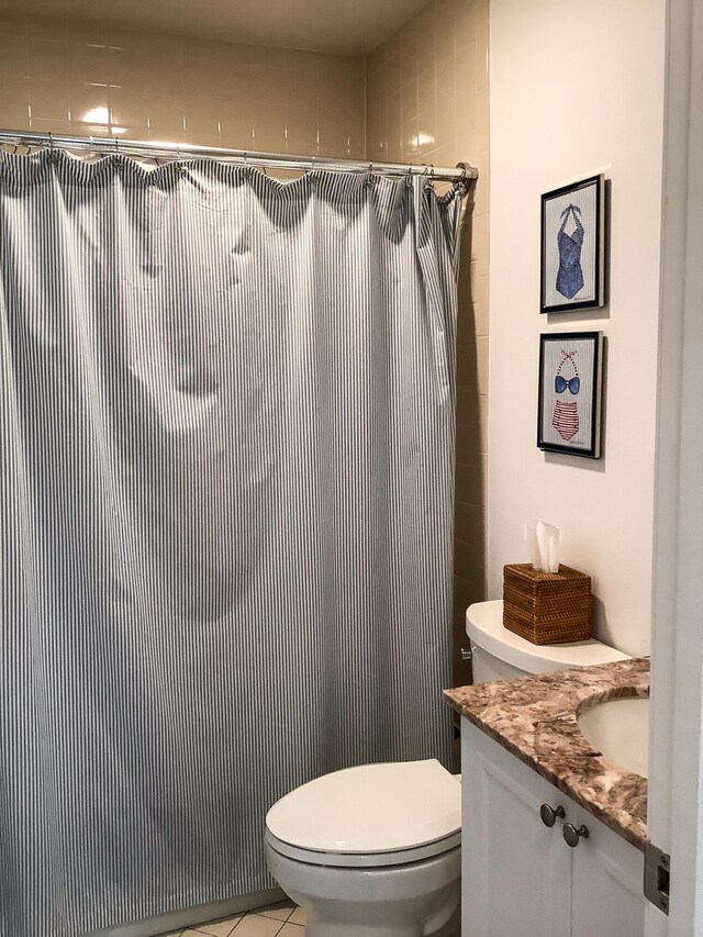 bathroom featuring vanity, a tile shower, and toilet