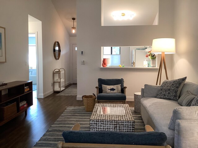 living room featuring baseboards, dark wood finished floors, and vaulted ceiling