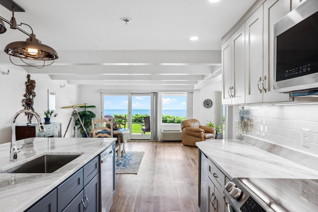 kitchen with light stone counters, sink, decorative backsplash, and stainless steel appliances