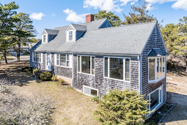 view of home's exterior with a shingled roof and a chimney