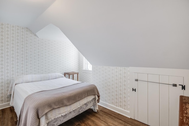 bedroom with baseboards, wallpapered walls, and wood finished floors
