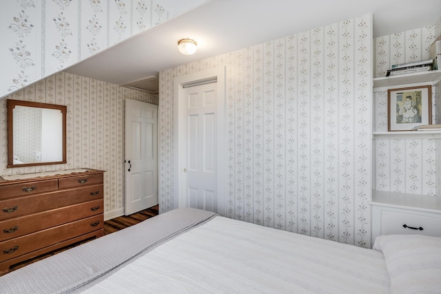 bedroom with a closet, wood finished floors, and wallpapered walls
