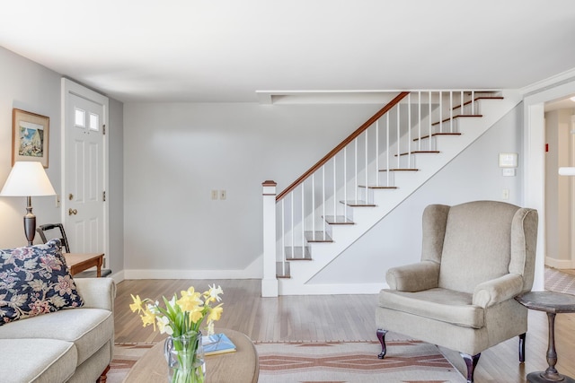 living area with wood finished floors, baseboards, and stairs