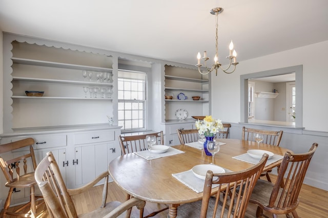 dining space with light wood finished floors and an inviting chandelier