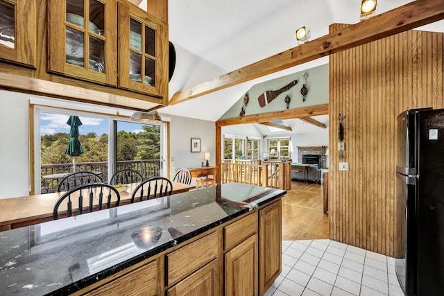 3 Amber Way, Truro, MA 02666 - kitchen featuring freestanding refrigerator, a fireplace, light tile patterned floors, dark stone countertops, and glass insert cabinets