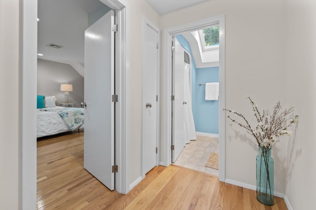 hallway featuring light hardwood / wood-style flooring and a skylight