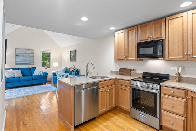 kitchen featuring sink, light hardwood / wood-style flooring, appliances with stainless steel finishes, vaulted ceiling, and kitchen peninsula