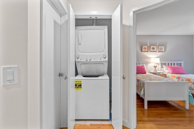 laundry area featuring stacked washer and clothes dryer and light wood-type flooring