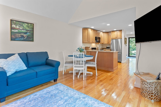 living room with sink, vaulted ceiling, and light hardwood / wood-style floors