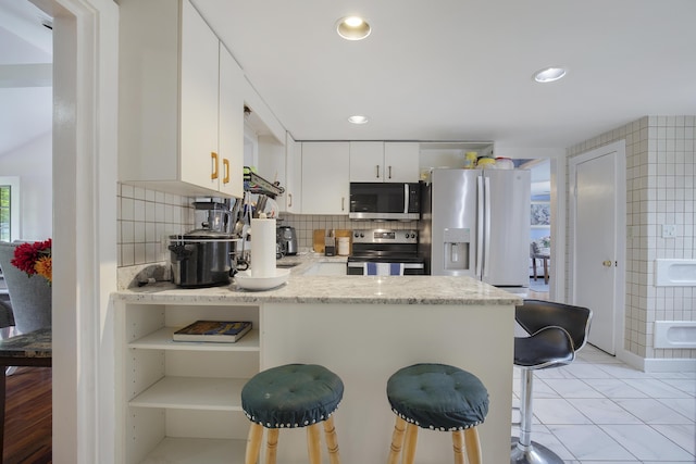 298 Oakland Rd, Hyannis, MA 02601 - kitchen with electric stove, refrigerator with ice dispenser, stainless steel microwave, a peninsula, and a kitchen breakfast bar