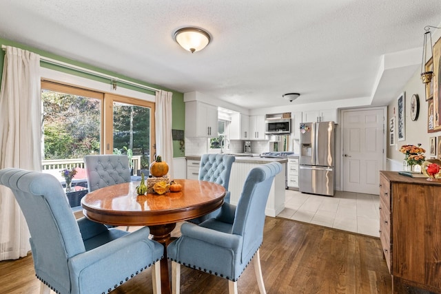 dining space featuring sink, light hardwood / wood-style flooring, and a textured ceiling