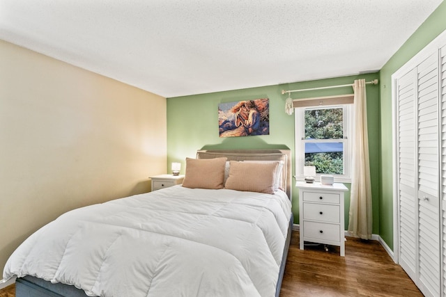 bedroom featuring a closet, dark wood-type flooring, and a textured ceiling