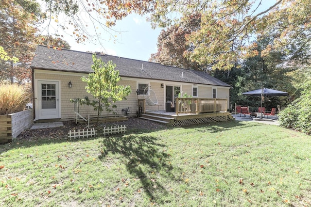 rear view of house with a patio, a lawn, and a wooden deck