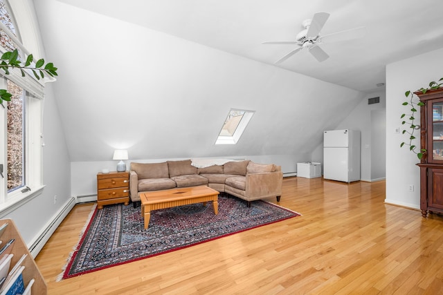 living area featuring light wood-type flooring, vaulted ceiling with skylight, and a baseboard radiator