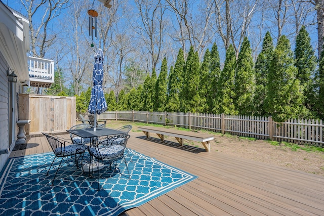 wooden terrace with outdoor dining area and a fenced backyard