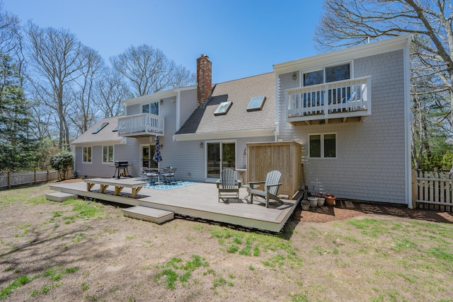 rear view of property with fence, a chimney, roof with shingles, and a balcony