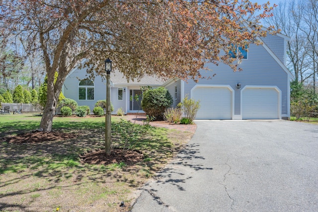 view of property hidden behind natural elements with a front lawn and aphalt driveway