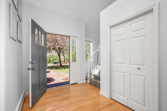 foyer featuring stairway, a baseboard heating unit, and light wood-style flooring
