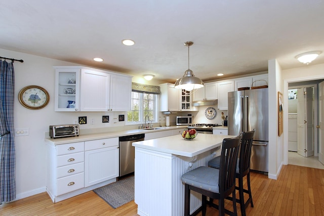 19 Featherbed Ln, Brewster, MA 02631 - kitchen featuring appliances with stainless steel finishes, a sink, light wood-type flooring, white cabinetry, and glass insert cabinets