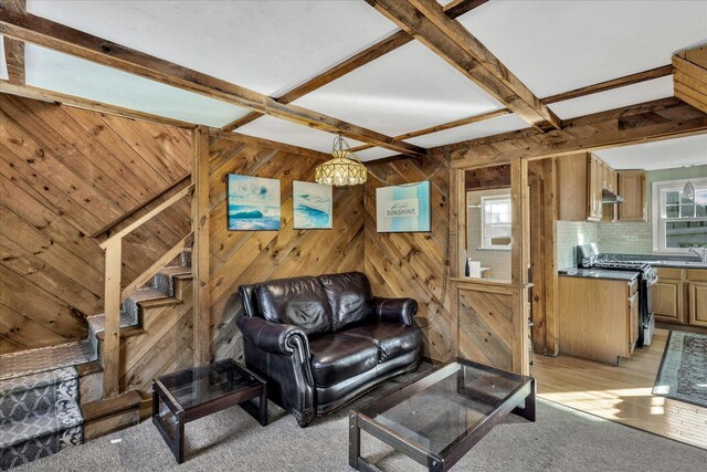 carpeted living room with coffered ceiling, sink, and beam ceiling